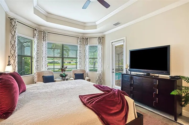 Bedroom with a ceiling fan, crown molding, a raised ceiling, and access to exterior