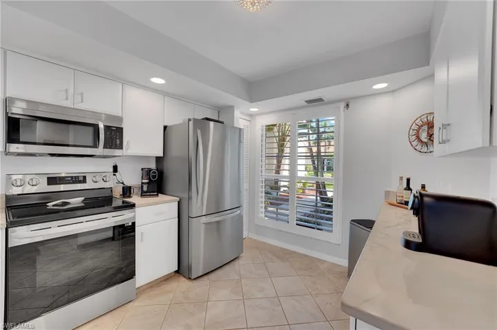 Natural light pours into the kitchen, enhanced by recessed lighting for a warm, layered ambiance, while custom plantation shutters offer the perfect balance of sun-filled brightness and refined privacy.