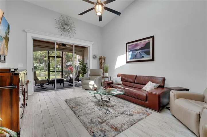 New plank-style tile flooring enhances the main living area, where soaring ceilings and captivating lake views create a bright, expansive, and effortlessly elegant atmosphere, beautifully finished with custom window framing that adds a refined architectural touch.