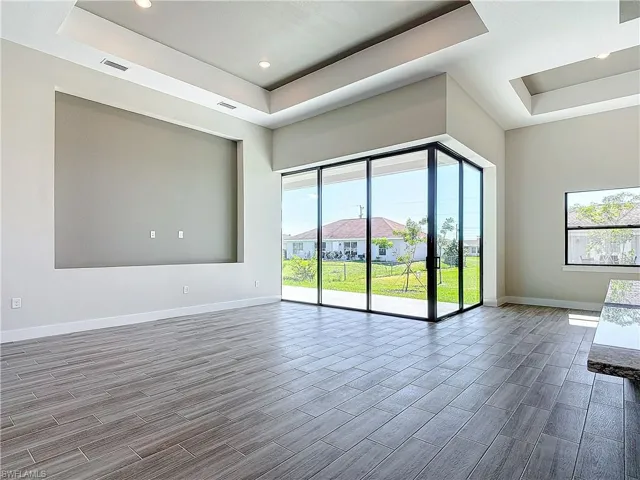 Spare room with a raised ceiling, baseboards, wood tiled floors, and recessed lighting