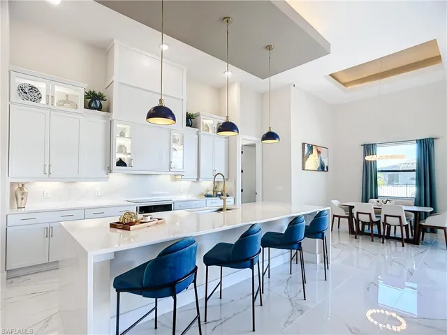Kitchen with pendant lighting, sink, a breakfast bar area, white cabinetry, and a center island with sink