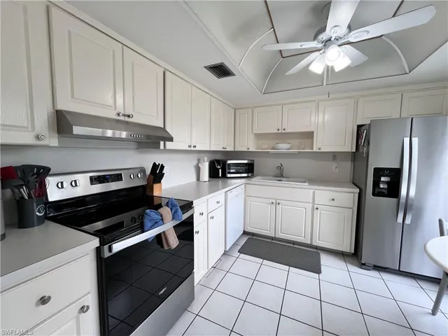 Kitchen with stainless steel appliances, light countertops, white cabinets and breakfast table