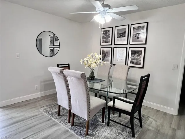 Dining space with a textured ceiling, a ceiling fan, and light wood-style flooring