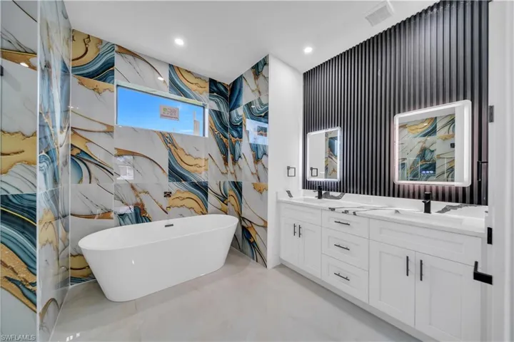 Bathroom featuring double vanity, a soaking tub, and recessed lighting