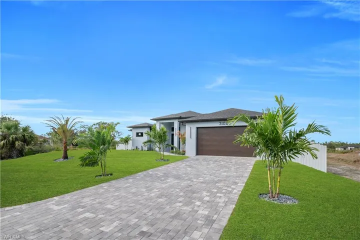Prairie-style house featuring a garage, decorative driveway, a front lawn, and stucco siding