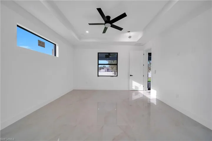 Empty room with a tray ceiling and a ceiling fan