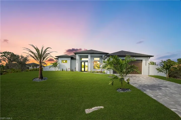 Prairie-style home featuring a front yard, decorative driveway, stucco siding, and a garage