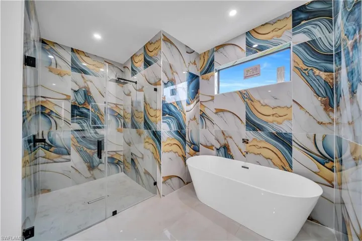 Full bath with a freestanding tub, a marble finish shower, and recessed lighting