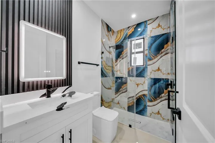 Full bathroom with a marble finish shower, vanity, and wallpapered walls