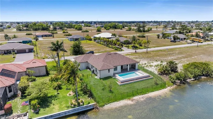 Aerial view of residential area featuring a nearby body of water and a pool