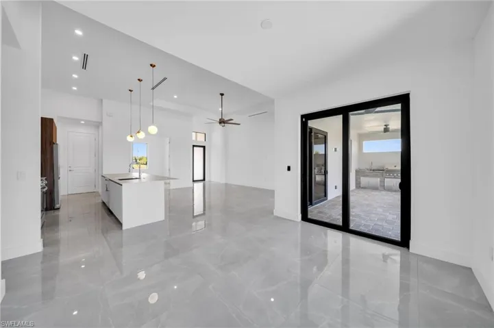 Kitchen with a center island with sink, open floor plan, a ceiling fan, decorative light fixtures, and light marble finish floors