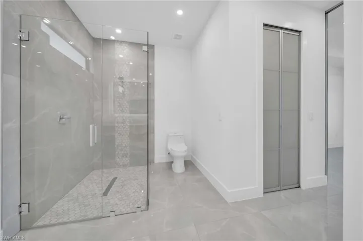 Bathroom with a marble finish shower, recessed lighting, and light tile patterned floors