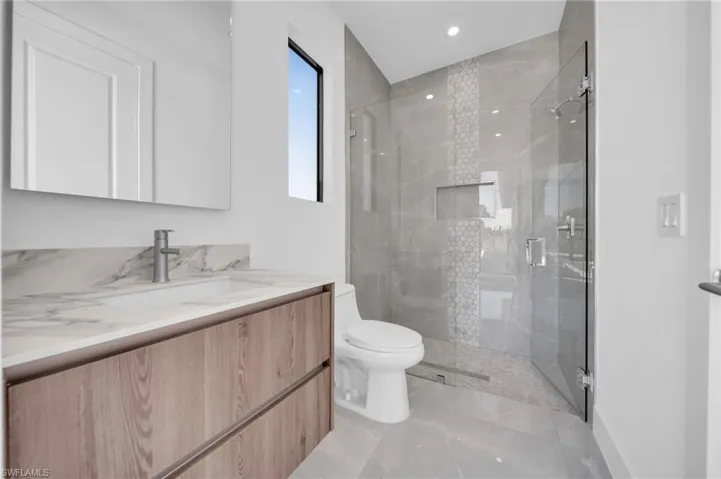 Full bathroom with a marble finish shower, vanity, and recessed lighting