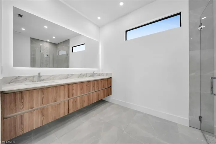 Full bath featuring a marble finish shower, plenty of natural light, recessed lighting, and double vanity