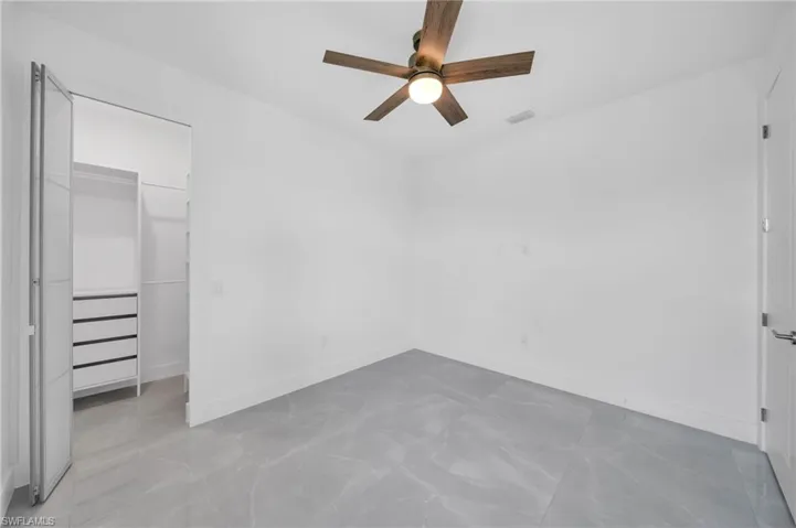 Unfurnished bedroom featuring a walk in closet and ceiling fan