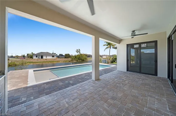 Outdoor pool featuring ceiling fan, a patio area, and a water view