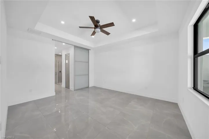 Empty room with a tray ceiling, ceiling fan, and recessed lighting