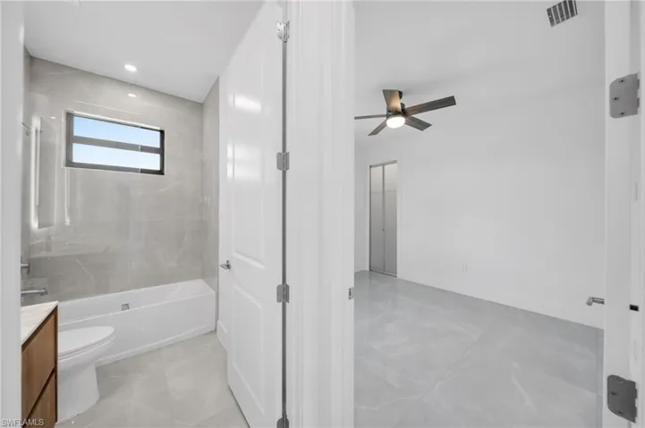 Full bath with vanity, shower / washtub combination, recessed lighting, a ceiling fan, and light marble finish floors