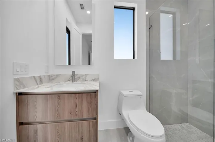 Full bath with vanity, a walk in shower, and recessed lighting