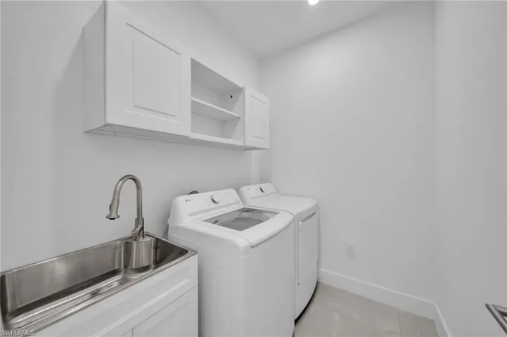 Washroom featuring washing machine and clothes dryer, light tile patterned floors, recessed lighting, and cabinet space