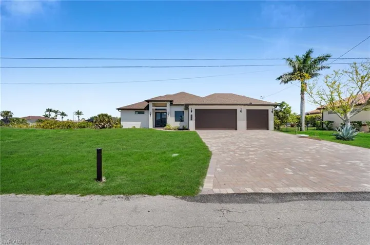 Prairie-style home featuring a front yard, decorative driveway, an attached garage, and stucco siding