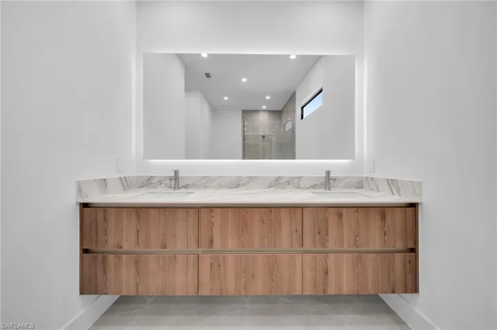 Full bath featuring a shower stall, recessed lighting, and double vanity