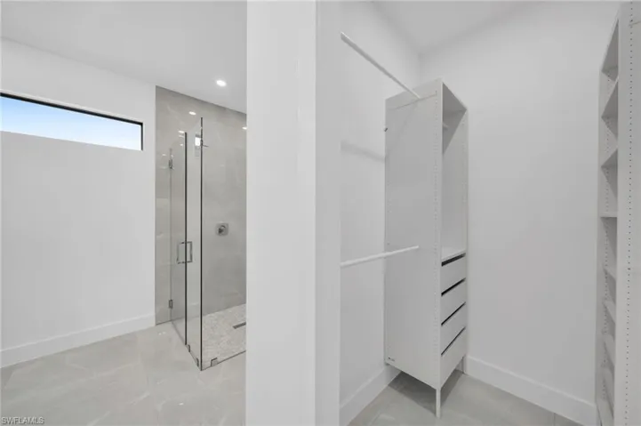 Bathroom with a shower stall, a spacious closet, and recessed lighting