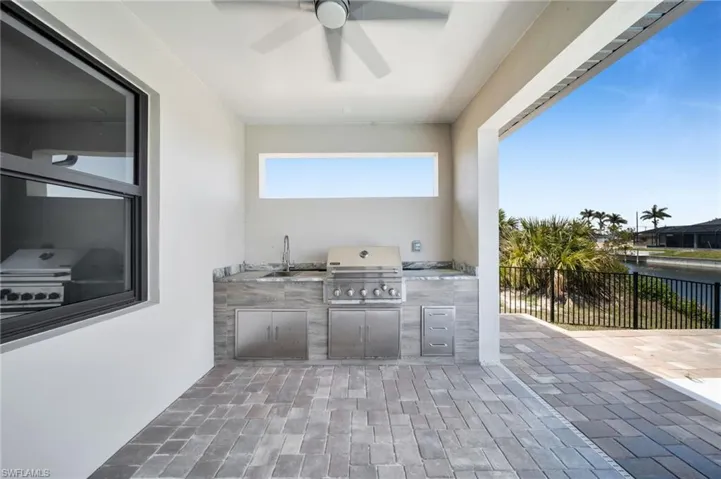 View of patio / terrace with an outdoor kitchen, ceiling fan, and a water view