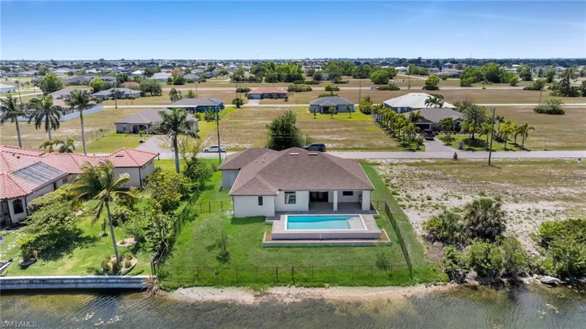 Aerial view of residential area featuring a large body of water and a pool area