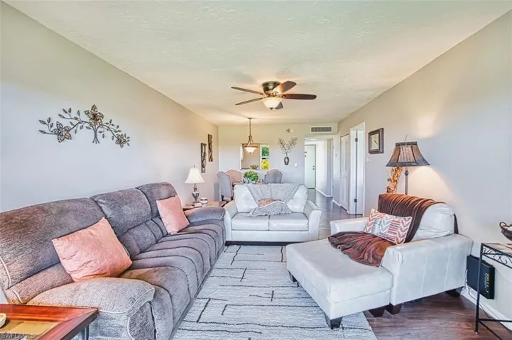Living room featuring ceiling fan, wood finished floors, and a textured ceiling