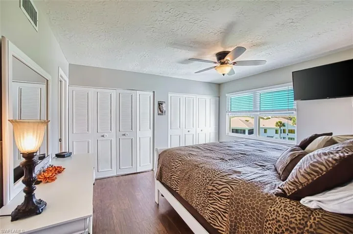 Master Bedroom featuring multiple closets, dark wood finished floors, a textured ceiling, and a ceiling fan