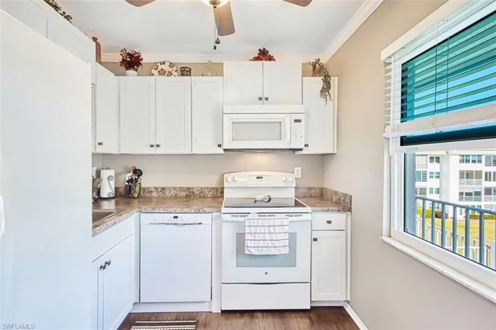 Kitchen with white appliances, white cabinetry, a ceiling fan, ornamental molding, and dark wood-style floors