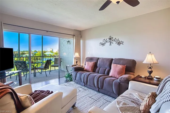 Living area featuring a textured ceiling, a ceiling fan, and wood finished floors