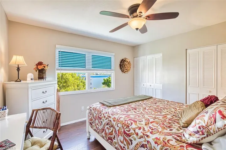 Quest Bedroom featuring multiple closets, dark wood-style flooring, and ceiling fan