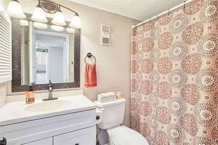 Full bathroom featuring vanity, a textured ceiling, and a shower with curtain