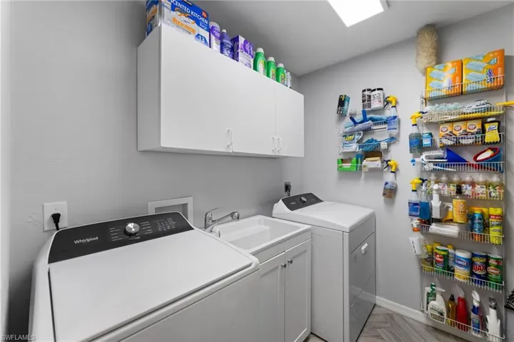 Laundry room with cabinets, washer and dryer, sink, and light parquet flooring