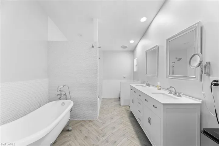 Bathroom featuring tile walls, vanity, parquet flooring, and independent shower and bath