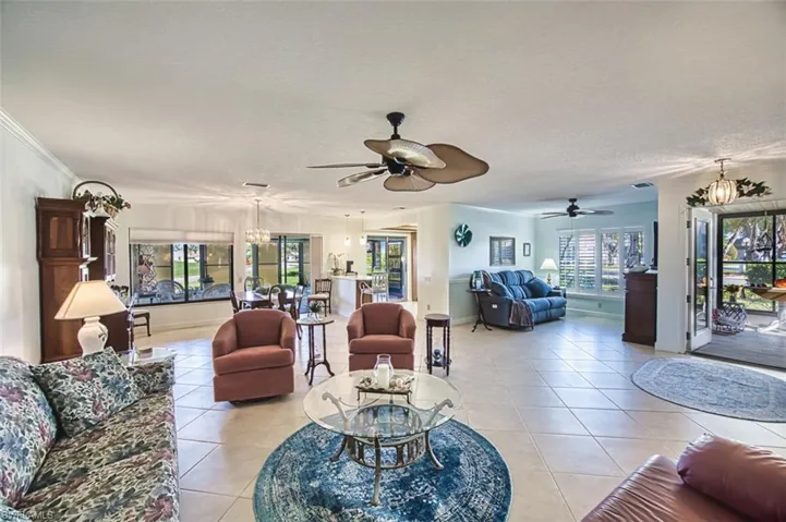 Living room with a chandelier, light tile patterned flooring, a ceiling fan, and a textured ceiling