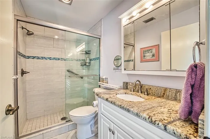 Full bath with vanity, a stall shower, and light tile patterned flooring