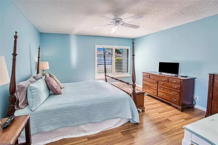 Bedroom with light wood-type flooring, ceiling fan, and a textured ceiling