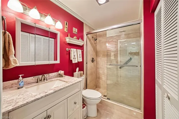 Bathroom with vanity, a shower stall, crown molding, and a closet