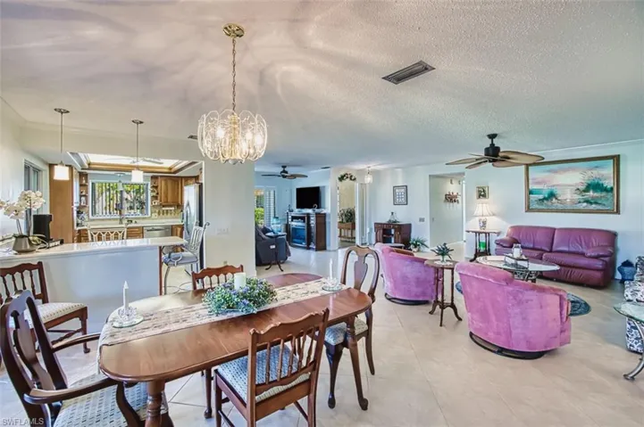 Dining area featuring a chandelier, a textured ceiling, light tile patterned floors, and ceiling fan