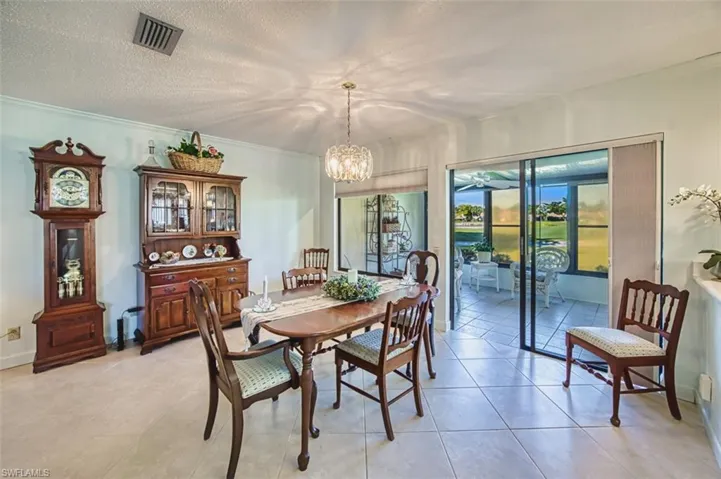 Dining space with a textured ceiling, a chandelier, crown molding, and light tile patterned flooring