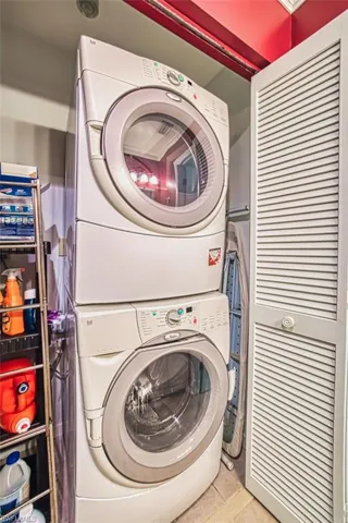 Laundry room with light tile patterned floors and stacked washer / dryer