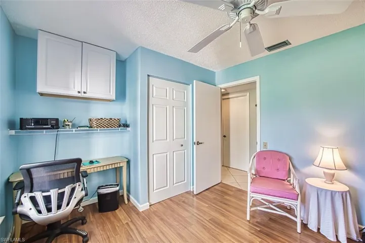 Sitting room featuring a textured ceiling, an office area, light wood-type flooring, and a ceiling fan