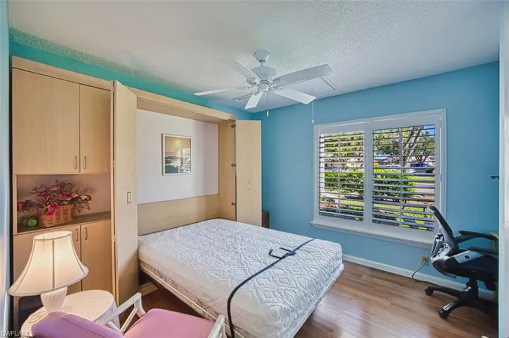 Bedroom with wood finished floors, a textured ceiling, and ceiling fan