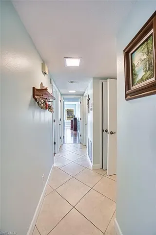 Corridor with light tile patterned floors and a textured ceiling