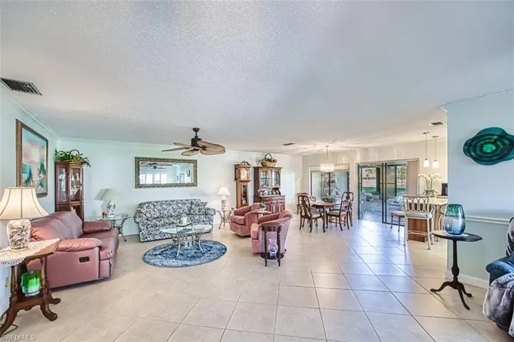 Living room with a textured ceiling, a ceiling fan, light tile patterned flooring, and plenty of natural light