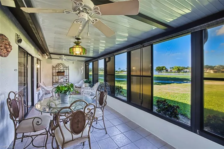 Sunroom with a ceiling fan, a water view, tile patterned flooring, and outdoor dining space
