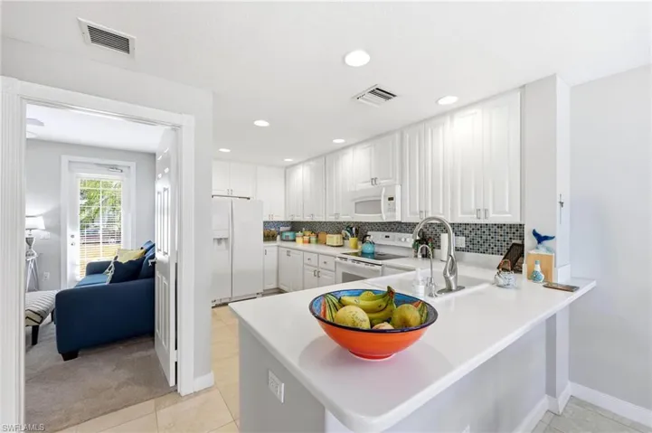Kitchen featuring light countertops, white appliances, white cabinets, a peninsula, and recessed lighting